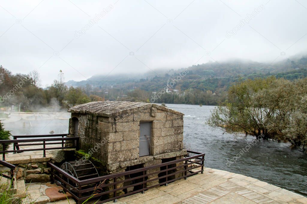 Old water mill Muino da Veiga and thermal hot springs by Minho riverbed in Ourense, Spain