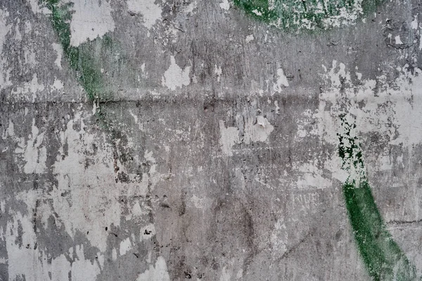 Old bulleting board wall with rests of worn peeled advertising posters, grunge background or texture