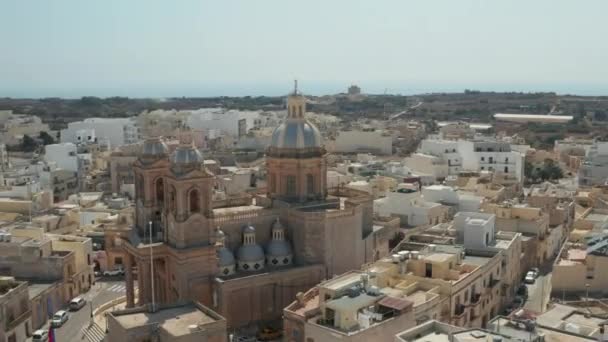 Mooie blauwe en bruine kerktorens in kleine mediterrane stad op Malta Island, schuif vanuit de lucht recht in zonsondergang licht — Stockvideo