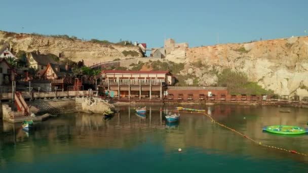 アンカーベイ,ゴゾ島,マルタのポパイ村水とボートによる住宅,空中ドローンは後方ドリーショット — ストック動画