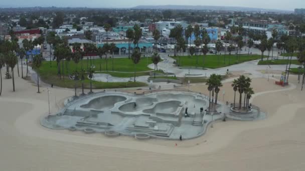 AERIAL: Otočte kolem Venice Beach Skatepark s motorkáři a palmy v dopoledních hodinách, Cloudy Los Angeles, Kalifornie — Stock video