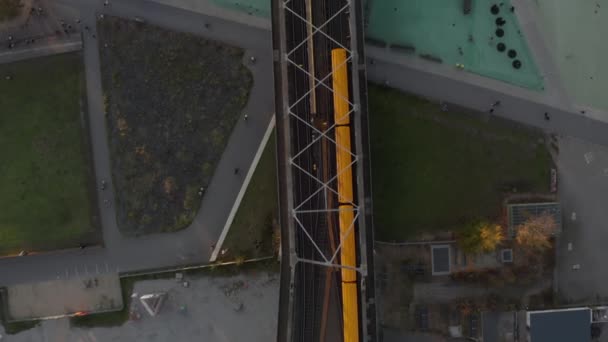 Żółty pociąg metra na moście przechodzącym przez park publiczny w Berlinie, Niemcy, Aerial Birds Eye Overhead Widok z góry na dół — Wideo stockowe