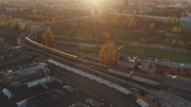 Метро Поезд с воздушной перспективы, проходящий через общественный парк в Берлине, Германия в желтых и оранжевых осенних цветах и закат золотой свет — стоковое видео