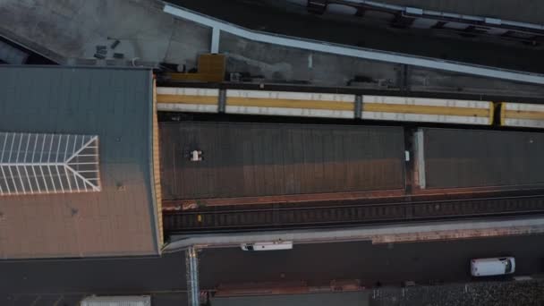 Trem amarelo entrando na estação de metrô elevada acima do solo em Berlim, Alemanha a partir da perspectiva aérea de observação aérea de aves — Vídeo de Stock