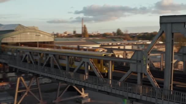 Gele metro Trein passeert brug door stedelijke omgeving in Berlijn, Duitsland in prachtige gouden uur Zonsondergang licht, Luchtfoto volgen — Stockvideo