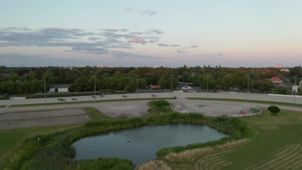 Heste med ryttere Udnyt væddeløb på væddeløbsbanen i Berlin, Tyskland ved Sunset fra Aerial Wide Angle Shot – Stock-video