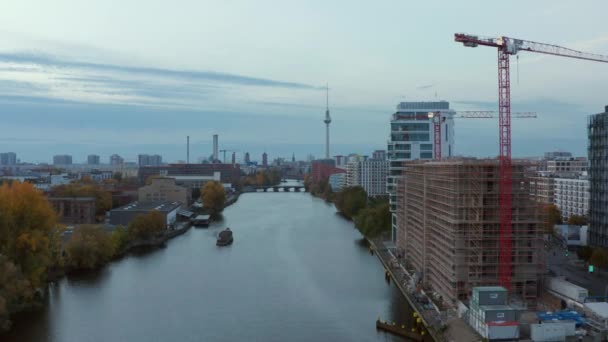 Río Spree con el paisaje de la ciudad de Berlín y el sitio de construcción en la orilla del río, plano de muñeca delantera de gran angular aéreo — Vídeos de Stock