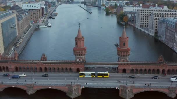 Oberbaum híd Berlinben, Németországban és sárga busz halad át Spree folyó nappal, légi Dolly előre széles lövés — Stock videók