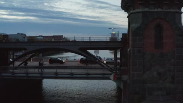 Fietsers en autoverkeer op de Berlijnse Oberbaum brug oud beroemd gebouw over de Spree rivier in de avond, antenne Volg Slide rechts — Stockvideo