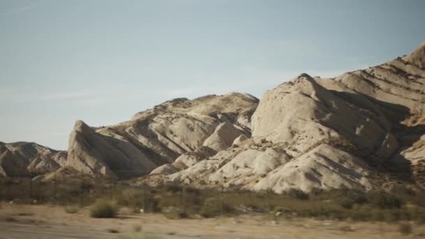 California Nature à côté d'une higway avec panneau jaune, passant devant des rochers beiges bruns et du sable — Video