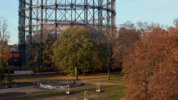 Beroemde gasmeter in Berlijn, Duitsland omgeven door Herfst gekleurde Bomen en Natuur in Big City, antenne lift omhoog onthullend schot — Stockvideo
