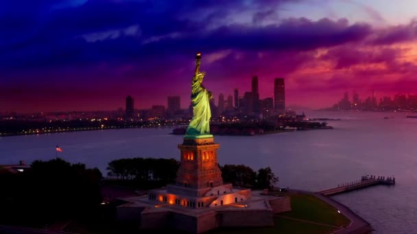 Légi kilátás ragyogó szabadságszobor körül, egy színes naplementében, sötét felhők hemzsegnek, New Yorkban, USA-ban - Orbit, drónlövés — Stock videók