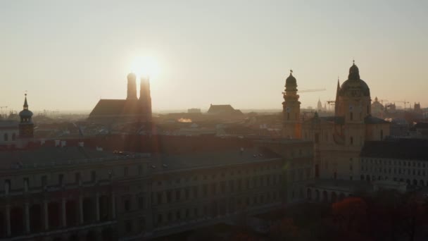 Nachmittagssonne lugt hinter der Silhouette der Frauenkirche im schönen Münchner Stadtbild hervor, Aufnahme an einem Wintertag, Luftaufnahme langsam vorwärts