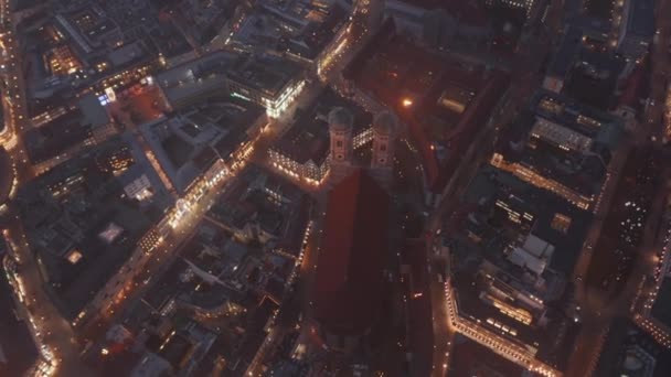 Cinematic Scenic Aerial Shot looking down on Frauenkirche Cathedral in Munich, Germany through the fog lowering above Beautiful Church in Dusk with City lights, Drone Aerial Birds Eye Top View — Stock Video
