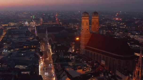 A famosa Catedral da Igreja Frauenkirche em Munique à noite, Dolly aérea para a frente se aproximando de duas torres de belo edifício antigo, Scenic City Lights brilhando — Vídeo de Stock