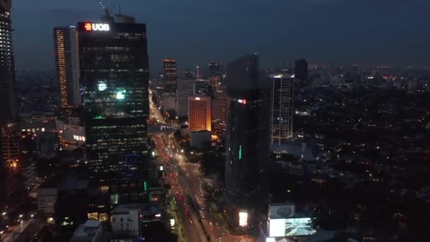 Dolly aérea disparó volando hacia rascacielos por encima del tráfico nocturno ocupado en la carretera en Yakarta, Indonesia — Vídeo de stock