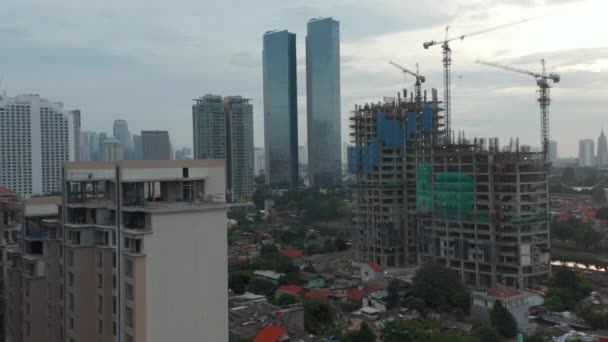 Photo aérienne de poupée volant à travers le centre-ville vers un gratte-ciel en construction à Jakarta, Indonésie — Video