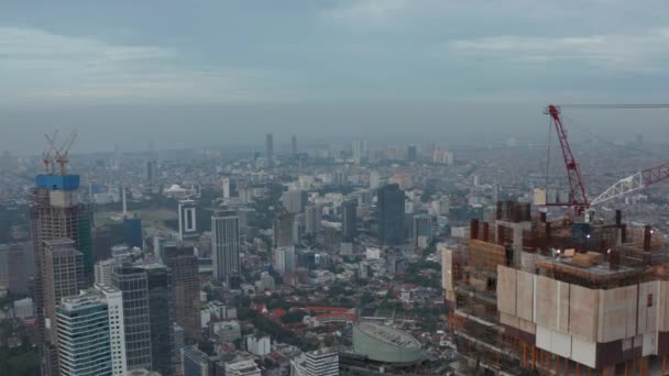 Foto de muñeca aérea que pasa por la parte superior del rascacielos en construcción volando hacia edificios en el centro de la ciudad de Yakarta, Indonesia — Vídeo de stock