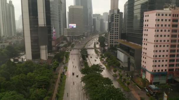 Muñeca voladora aérea baja en la toma de pedestal de tráfico de varios carriles que conduce al centro de la ciudad en un día lluvioso húmedo en Yakarta, Indonesia — Vídeo de stock