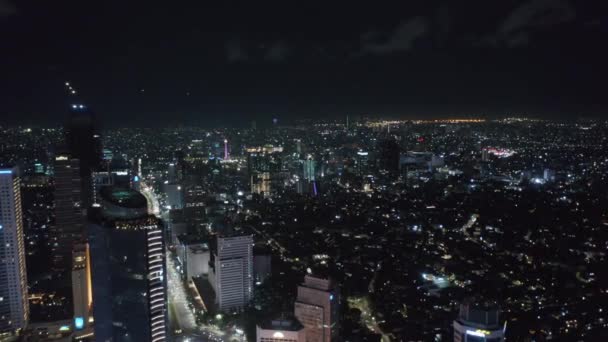 Tiro de boneca lenta larga aérea do impressionante centro da cidade moderna à noite com arranha-céus e movimentada rodovia multi-pista com luzes em Jacarta, Indonésia — Vídeo de Stock