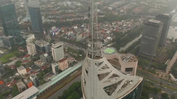 Воздушный пьедестал наклоняется в верхнюю часть небоскреба Wisma 46 в Джакарте, Индонезия в пасмурный день — стоковое видео
