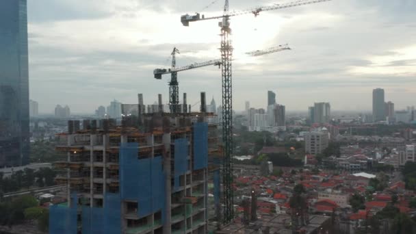 Close up aerial view of crane lowering an object on the roof of the skyscraper under construction in Jakarta, Indonesia — Stock Video