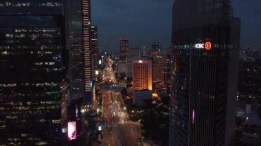 Jakarta, Endonezya 'daki Selamat Datang Anıt kavşağında gece trafiğine doğru inen hava kulesi görüntüsü