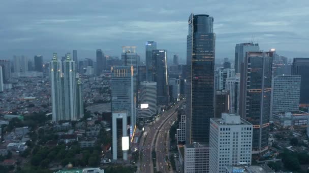 Photo aérienne de poupée montante à la suite d'un trafic à voies multiples achalandé entre des gratte-ciel modernes au crépuscule à Jakarta, en Indonésie — Video