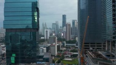 Jakarta, Endonezya 'daki iki cam gökdelen arasında şehir merkezindeki gökdelenlere doğru giden hava aracı.