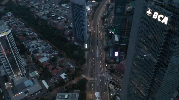 Vista aérea basculante después de ocupado tráfico de varios carriles en la ciudad moderna con rascacielos altos en Yakarta, Indonesia — Vídeo de stock