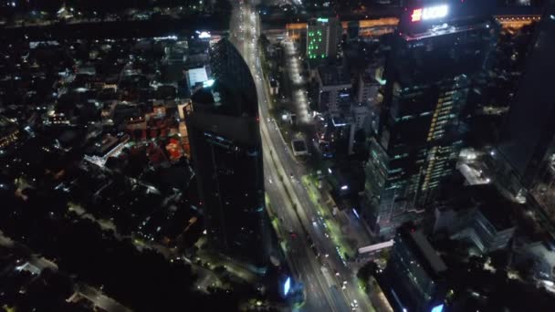 Tiro de inclinación aérea después de tráfico ocupado en carretera de varios carriles a través del centro de Yakarta por la noche — Vídeo de stock