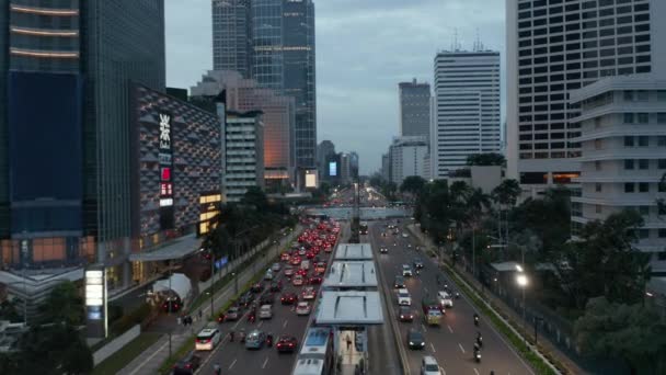 Vista aérea de vuelo bajo de la concurrida carretera de varios carriles con tráfico de automóviles cerca de la rotonda por la noche con hermosas luces de la ciudad brillando en el centro de Yakarta, Indonesia — Vídeo de stock