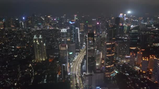 Leereszkedő légi piedesztális felvétel éjszakai autópálya forgalom keresztül forgalmas modern városközpont Jakarta — Stock videók