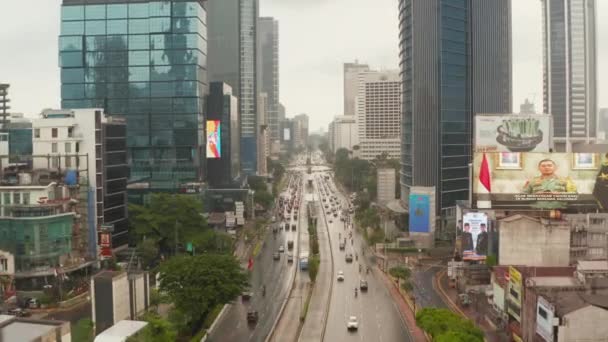Vuelo lento plano de dolly aérea baja de tráfico denso de la autopista en el centro de la ciudad moderna entre los rascacielos en Yakarta — Vídeo de stock