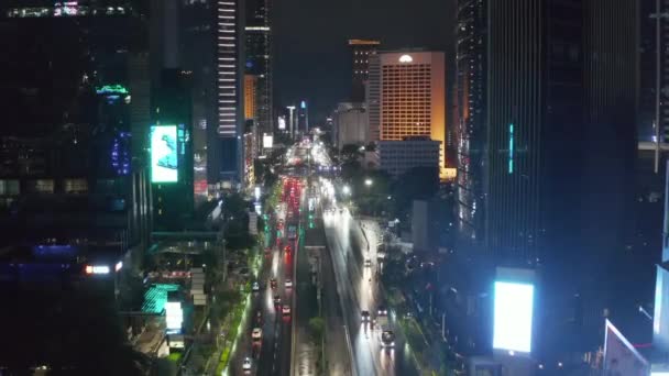 Pedestal descendente aéreo tiro de tráfego noturno em uma movimentada estrada da cidade cercada por arranha-céus altos em Jacarta, Indonésia — Vídeo de Stock