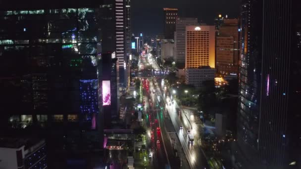 Pedestal descendente aéreo disparado volando hacia los lados del concurrido tráfico de varios carriles de la ciudad por la noche en el centro de la ciudad de Yakarta — Vídeo de stock