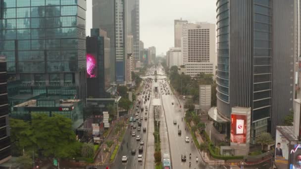 Pedestal aéreo ascendente y descendente plano de tráfico de varios carriles en el centro urbano de la ciudad entre rascacielos altos en Yakarta — Vídeo de stock