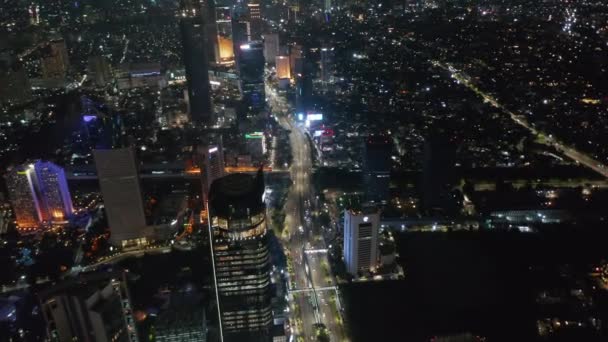 Amplia vista aérea del tráfico de carreteras de varios carriles por la noche en el moderno centro de la ciudad de Yakarta con rascacielos altos — Vídeo de stock