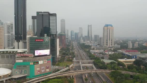 Vista amplia de dolly aérea de múltiples carreteras de varios carriles ocupados a través del centro de la ciudad moderna con rascacielos en Yakarta — Vídeo de stock