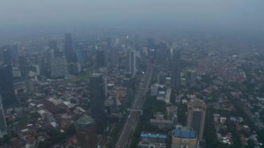 Gökdelenleri ve Jakarta 'daki yoğun yerleşim bölgeleri ile dolu modern şehir merkezinden geçen çoklu şeritli otoyolun havadan geniş açılışı.