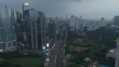 Akşamları yoğun bir otoyoldaki trafiğin ardından Jakarta 'daki yüksek gökdelenler ve atletizm sahalarıyla çevrili hava aracı görüntüsü.