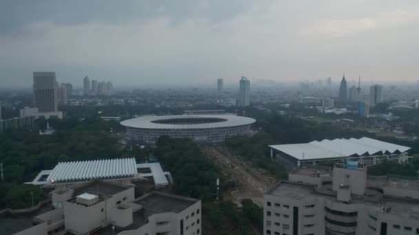 Široká letecká Dolly záběr moderní atletické Gelora Bung Karno stadion v centru města a panorama města v pozadí v Jakartě — Stock video