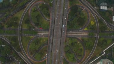 Yoğun araba trafiğinin yukarıdan aşağıya tepeden aşağıya bakan görüntüsü. Bir otoyoldaki modern geniş çok şeritli kavşakta.