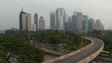 Yoğun araba trafiğiyle üst geçitten geçerken ve Jakarta şehrinin gökdelenli manzarasını gözler önüne sererken,