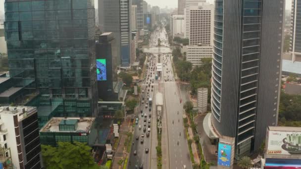 Pedestal aéreo disparado ascendiendo entre dos rascacielos de vehículos en una concurrida autopista de varios carriles en el moderno centro de la ciudad de Yakarta — Vídeo de stock