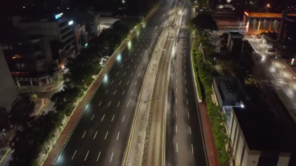 现代城市中心空旷的多车道公路，夜间摩天大楼的低空空中倾斜拍 — 图库视频影像
