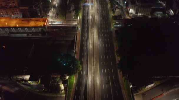 Tiro basculante aéreo después de un coche de policía en la autopista vacía de varios carriles por la noche en la gran ciudad metropolitana durante el bloqueo del coronavirus — Vídeo de stock