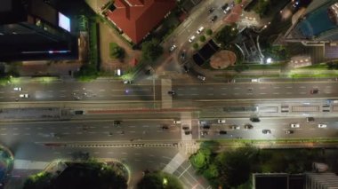 Tepe üstü kuşların gözü Asya 'nın büyük bir şehrinde gece yarısı kalabalık bir kavşaktan geçen araba ve motosikletlerin üzerinde.