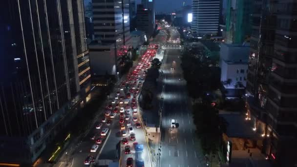 Aerial dolly shot of cars merging into a multi lane stopped traffic at a traffic light in urban city center — Stock Video