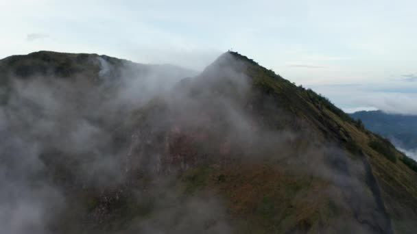 Εναέρια φορτηγό πυροβόλησε πετούν πέρα από την κορυφή του βουνού ενός ενεργού ηφαιστείου στο τροπικό κλίμα και εξαφανίζονται στην ομίχλη — Αρχείο Βίντεο